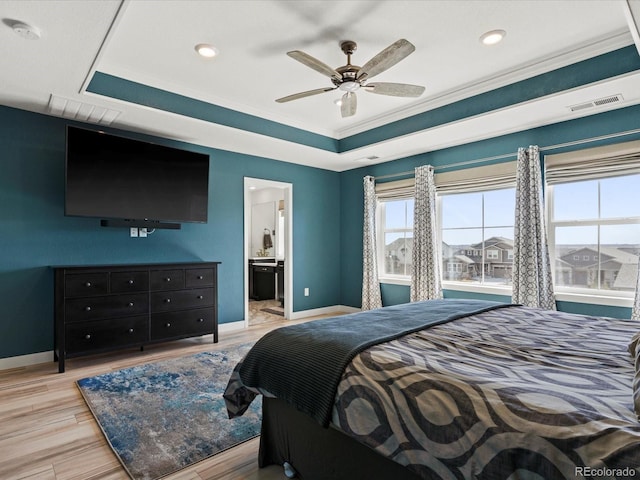 bedroom featuring visible vents, baseboards, light wood-type flooring, and a tray ceiling