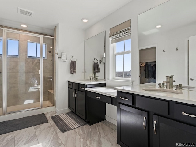 full bathroom with visible vents, two vanities, a stall shower, a sink, and marble finish floor