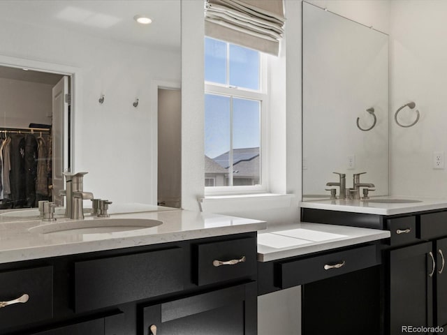 bathroom featuring a spacious closet, recessed lighting, and vanity