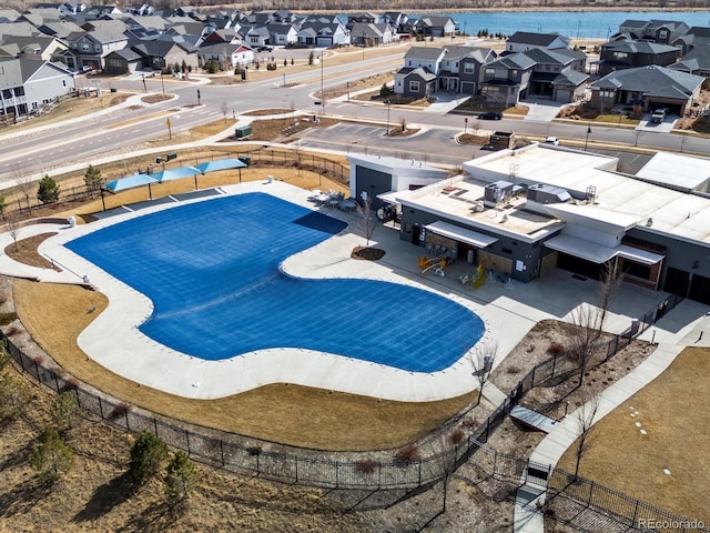 community pool featuring a residential view, a fenced backyard, a water view, and a patio area