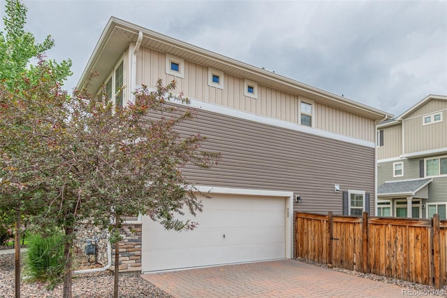 18112 E 104th Way, Commerce City, CO 80022 - view of side of property featuring board and batten siding, a garage, and decorative driveway