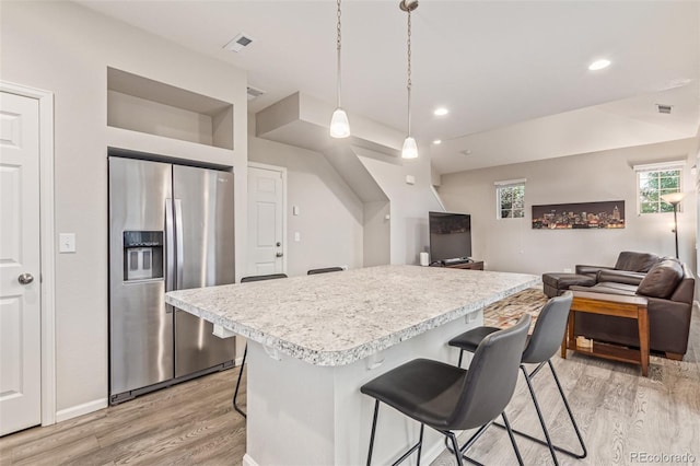18112 E 104th Way, Commerce City, CO 80022 - kitchen featuring stainless steel fridge with ice dispenser, light wood-type flooring, light countertops, a breakfast bar area, and open floor plan
