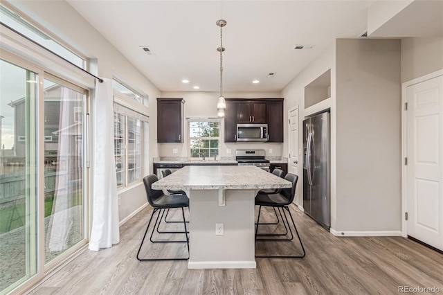 18112 E 104th Way, Commerce City, CO 80022 - kitchen with appliances with stainless steel finishes, dark brown cabinets, a kitchen breakfast bar, light wood-type flooring, and baseboards