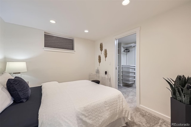 carpeted bedroom with a walk in closet, a closet, baseboards, and recessed lighting