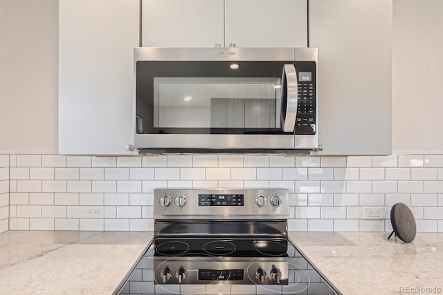 kitchen with stainless steel appliances, tasteful backsplash, and light stone countertops