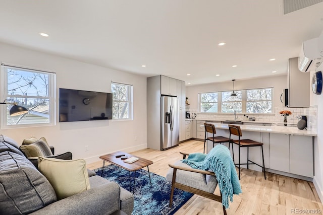 living room with light wood-type flooring, recessed lighting, baseboards, and a wall mounted AC