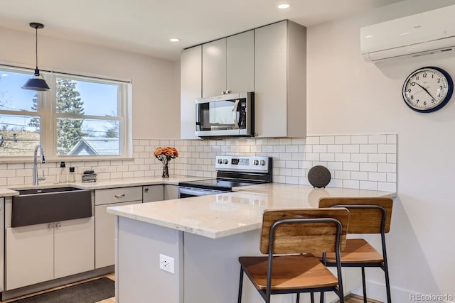 kitchen with a wall unit AC, tasteful backsplash, appliances with stainless steel finishes, a sink, and a peninsula