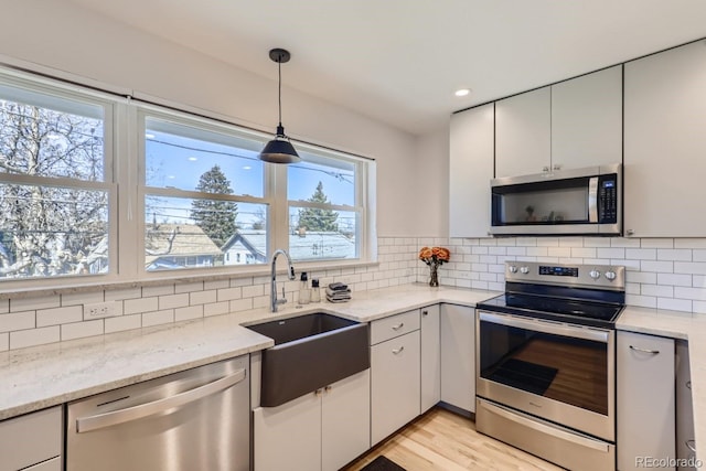 kitchen with stainless steel appliances, tasteful backsplash, a sink, and pendant lighting