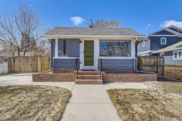 bungalow with a shingled roof and fence