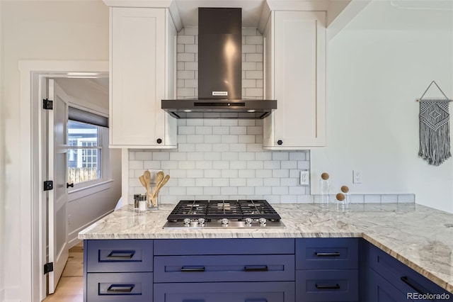 4441 N Meade St, Denver, CO 80211 - kitchen with decorative backsplash, stainless steel gas cooktop, wall chimney range hood, white cabinetry, and blue cabinetry