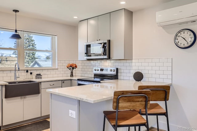 4441 N Meade St, Denver, CO 80211 - kitchen featuring a sink, gray cabinetry, an AC wall unit, a peninsula, and stainless steel appliances