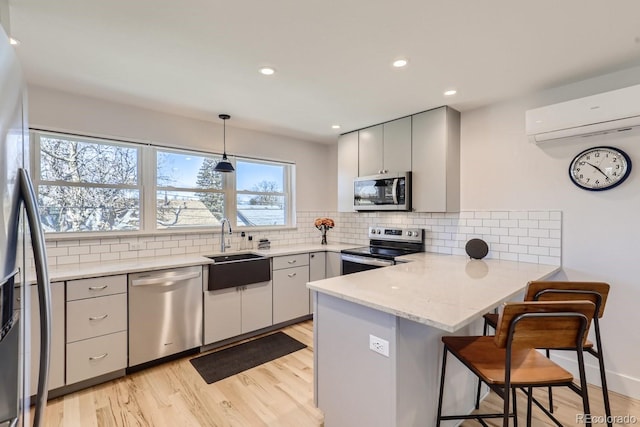4441 N Meade St, Denver, CO 80211 - kitchen featuring light wood-type flooring, a wall mounted air conditioner, a sink, a peninsula, and stainless steel appliances