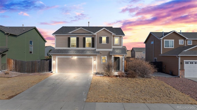 traditional-style house featuring driveway, an attached garage, and fence