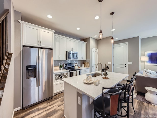 15269 W 69th Cir Unit A, Arvada, CO 80007 - kitchen with stainless steel appliances, wood finished floors, an island with sink, tasteful backsplash, and recessed lighting