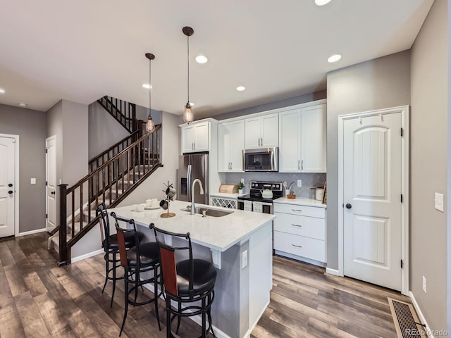 15269 W 69th Cir Unit A, Arvada, CO 80007 - kitchen featuring stainless steel appliances, dark wood-style floors, white cabinetry, a kitchen island with sink, and a breakfast bar