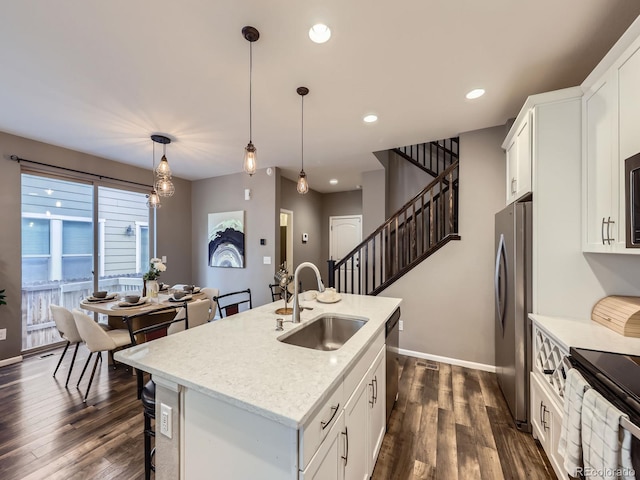 15269 W 69th Cir Unit A, Arvada, CO 80007 - kitchen with appliances with stainless steel finishes, dark wood-type flooring, white cabinetry, hanging light fixtures, and a kitchen breakfast bar