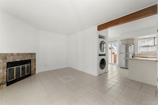 interior space featuring beamed ceiling, stacked washing maching and dryer, and light tile patterned floors