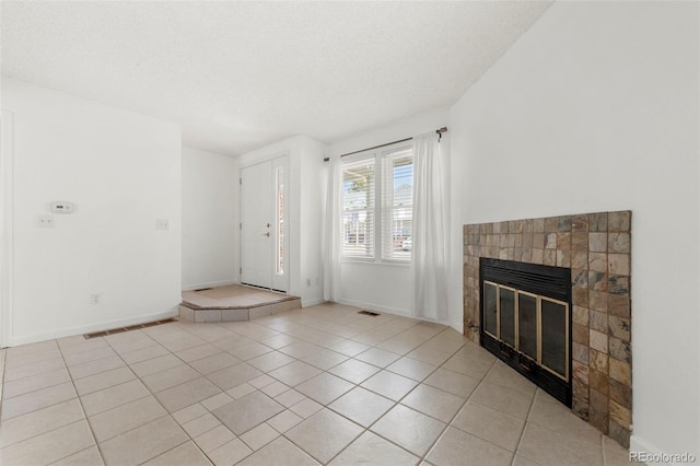 unfurnished living room with a tile fireplace, a textured ceiling, and light tile patterned flooring