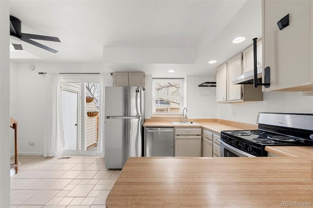 kitchen with a wealth of natural light, sink, light tile patterned floors, and stainless steel appliances