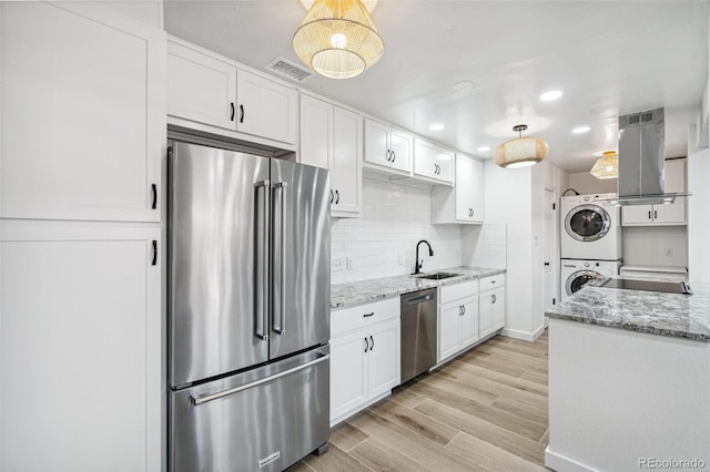 7995 E Mississippi Ave Unit A4, Denver, CO 80247 - kitchen featuring appliances with stainless steel finishes, stacked washing machine and dryer, island exhaust hood, a sink, and white cabinetry