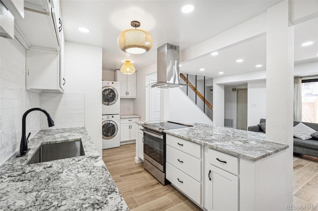 7995 E Mississippi Ave Unit A4, Denver, CO 80247 - kitchen with stacked washer and clothes dryer, stainless steel range with electric stovetop, island range hood, a sink, and white cabinets