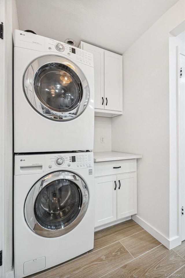 7995 E Mississippi Ave Unit A4, Denver, CO 80247 - washroom featuring estacked washer and dryer, cabinet space, baseboards, and light wood-style floors