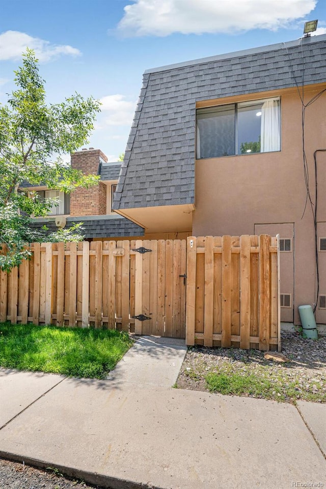 7995 E Mississippi Ave Unit A4, Denver, CO 80247 - view of side of property with a shingled roof, a gate, mansard roof, and stucco siding