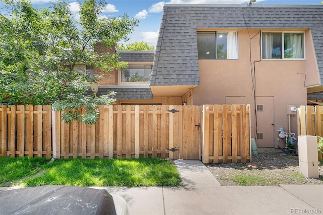7995 E Mississippi Ave Unit A4, Denver, CO 80247 - view of side of home with roof with shingles, a gate, mansard roof, and stucco siding