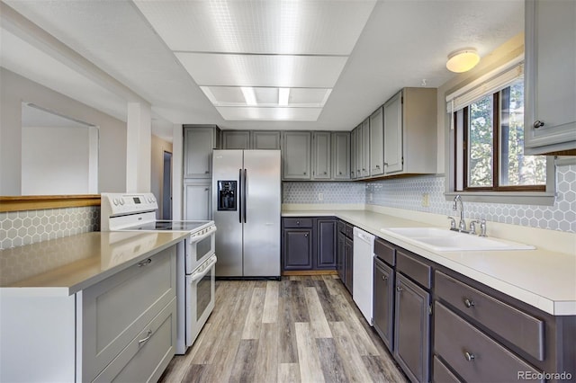 255 Park View Dr, Fairplay, CO 80440 - kitchen featuring decorative backsplash, white appliances, light wood-style floors, gray cabinets, and a sink