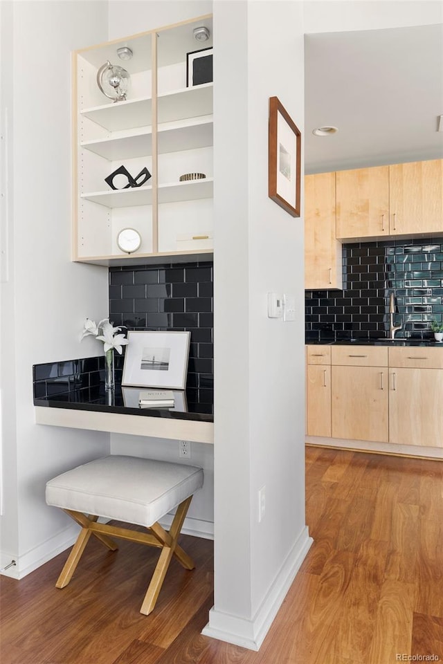 interior space featuring backsplash, light brown cabinetry, and light wood-type flooring