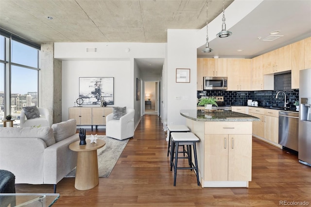 kitchen featuring appliances with stainless steel finishes, light brown cabinets, and dark wood-type flooring