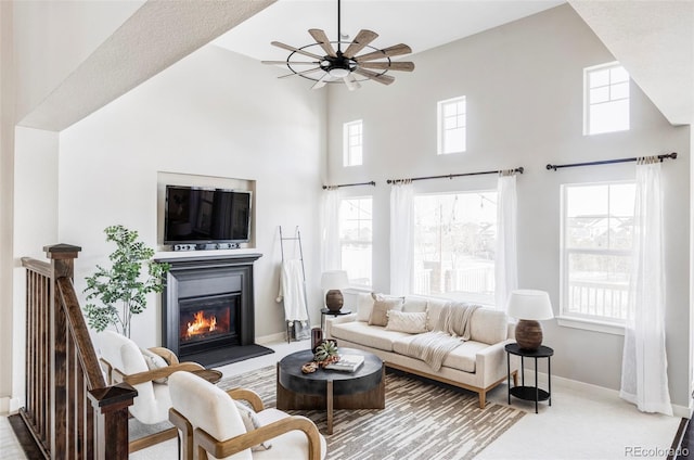 carpeted living room featuring a towering ceiling and ceiling fan