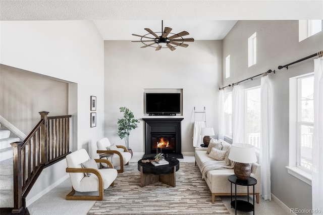 carpeted living room with ceiling fan, plenty of natural light, and a textured ceiling