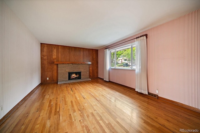 7077 Dudley Dr, Arvada, CO 80004 - unfurnished living room featuring light wood finished floors, a fireplace, and wood walls