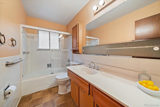 7077 Dudley Dr, Arvada, CO 80004 - bathroom with tile walls, vanity, combined bath / shower with glass door, and wainscoting