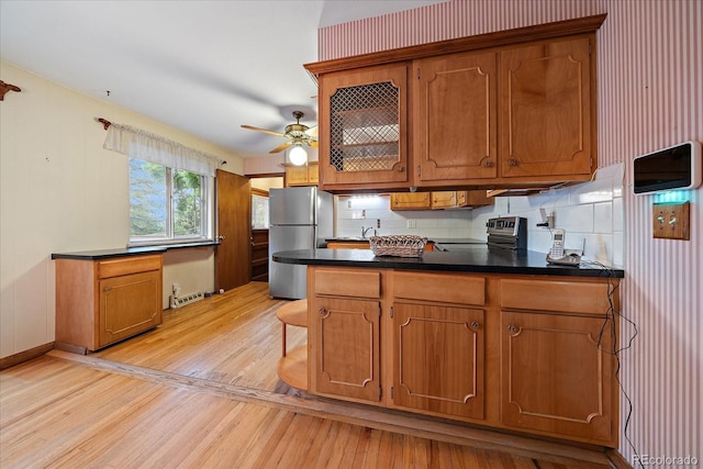 7077 Dudley Dr, Arvada, CO 80004 - kitchen with freestanding refrigerator, light wood-type flooring, brown cabinetry, and dark countertops