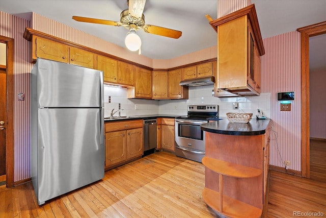 7077 Dudley Dr, Arvada, CO 80004 - kitchen featuring stainless steel appliances, dark countertops, under cabinet range hood, open shelves, and light wood-style floors
