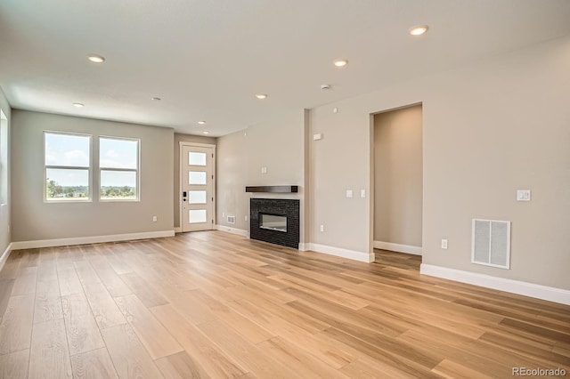 2491 W 69th Pl, Denver, CO 80221 - unfurnished living room with light wood finished floors, recessed lighting, and a glass covered fireplace