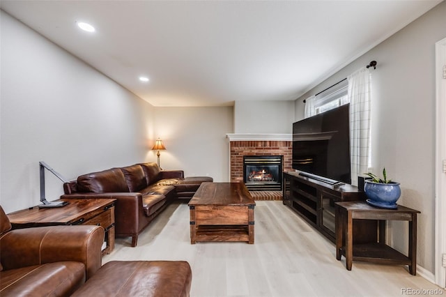 living room with light wood-type flooring and a brick fireplace