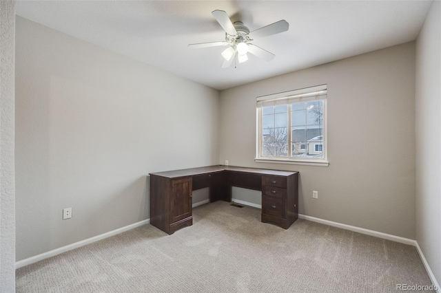 unfurnished office featuring ceiling fan and light carpet