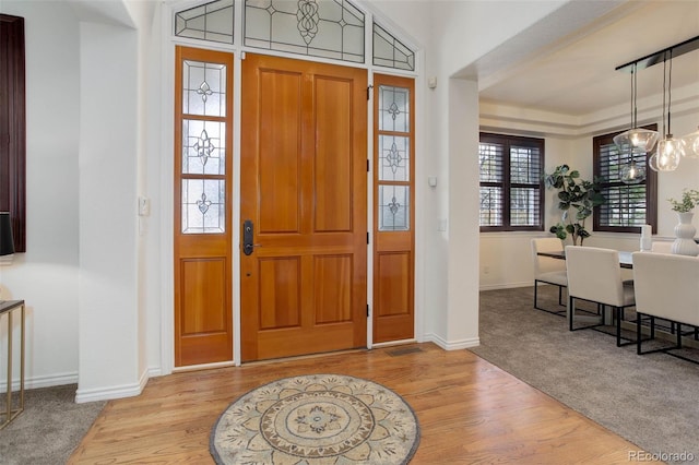 foyer entrance featuring an inviting chandelier, baseboards, and wood finished floors