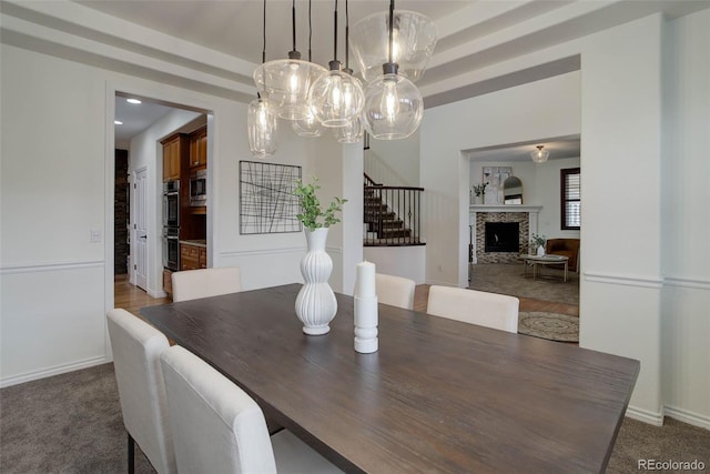 dining space featuring carpet floors, a fireplace, stairway, recessed lighting, and a notable chandelier