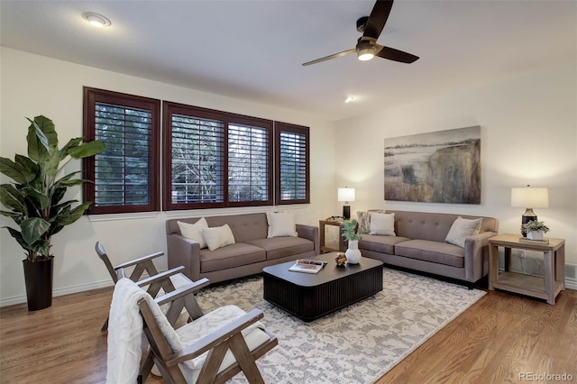 living room featuring baseboards, ceiling fan, and wood finished floors