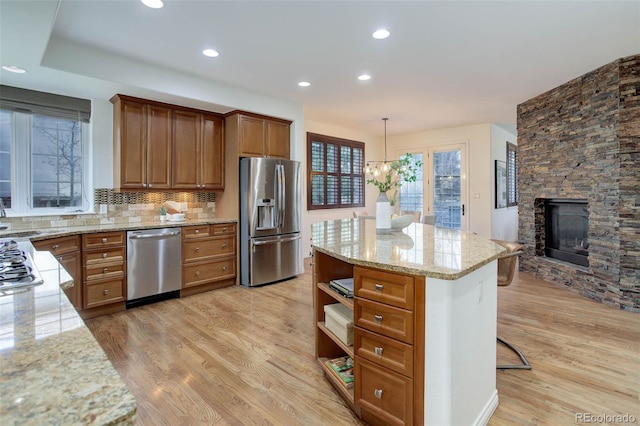 kitchen with open shelves, light wood-style floors, brown cabinets, light stone counters, and stainless steel appliances