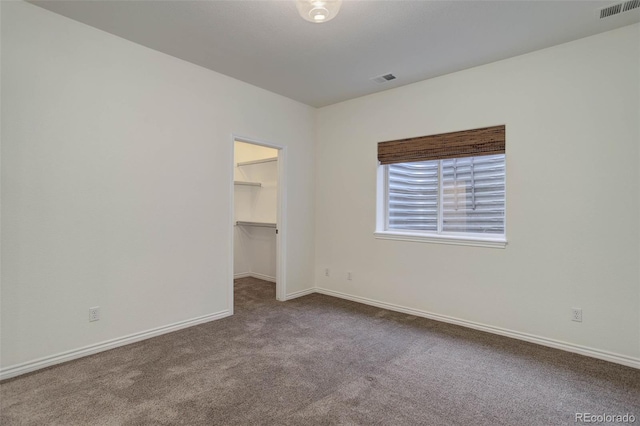 spare room with baseboards, visible vents, and dark carpet