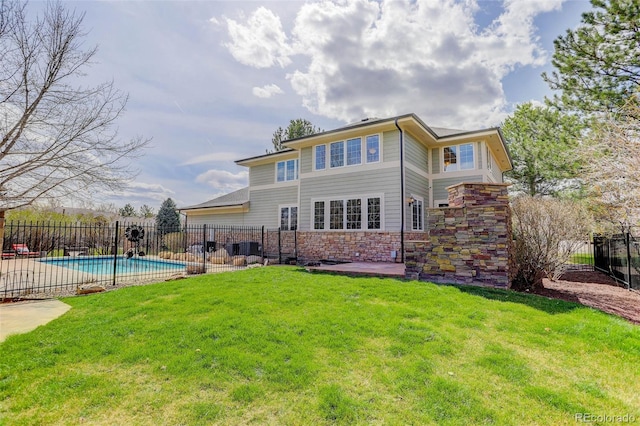 rear view of property with fence, stone siding, a fenced in pool, a patio area, and a yard
