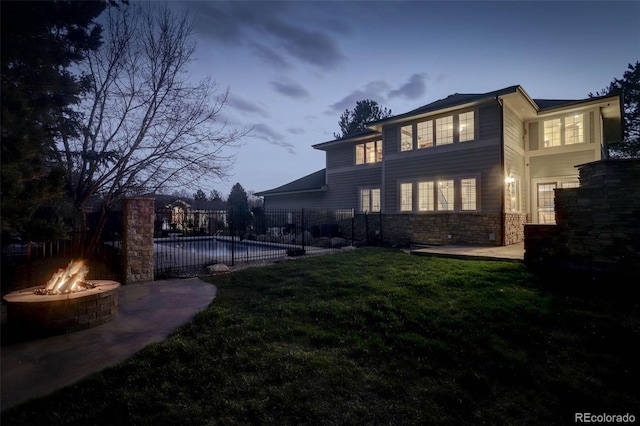 back of property with a lawn, fence, a fenced in pool, a patio, and a fire pit