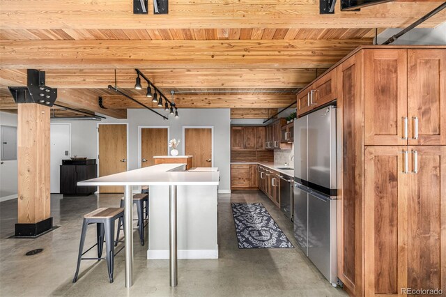 2955 Inca St Unit 1H, Denver, CO 80202 - kitchen with stainless steel appliances, finished concrete floors, a wooden ceiling with exposed beams, a center island, and a breakfast bar area