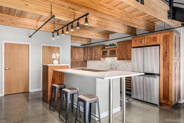 2955 Inca St Unit 1H, Denver, CO 80202 - kitchen with freestanding refrigerator, a wooden ceiling with exposed beams, brown cabinets, concrete floors, and light countertops
