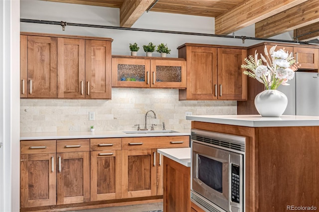 2955 Inca St Unit 1H, Denver, CO 80202 - kitchen with stainless steel microwave, brown cabinets, decorative backsplash, light countertops, and glass insert cabinets